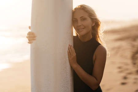 Beautiful surfer woman on the beach at sunsetの写真素材