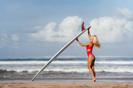 Surf woman with long blonde hair go to ocean.の写真素材