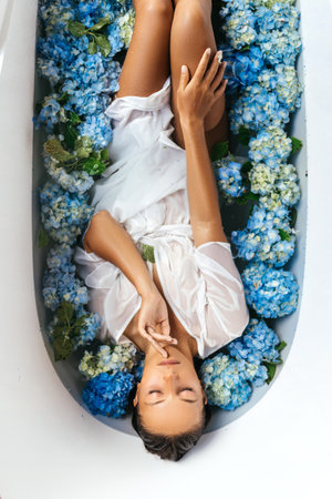 Woman relaxing in bath with tropical blue hydrangea.の写真素材