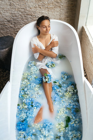 Woman relaxing in bath with tropical blue hydrangea.