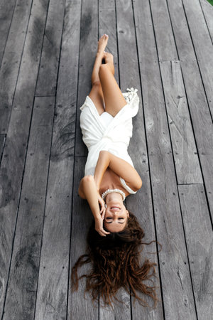 Photo of beautiful lady in white dress laying on the wooden floor,summer accessories.の写真素材