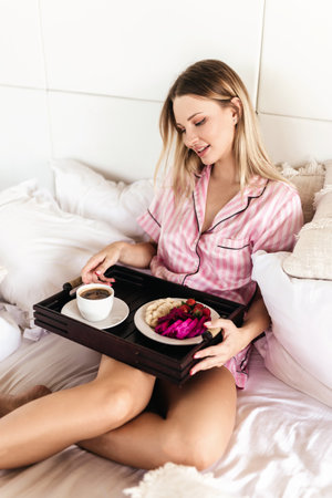 Young woman working at home in the bedroom during morning breakfastの写真素材