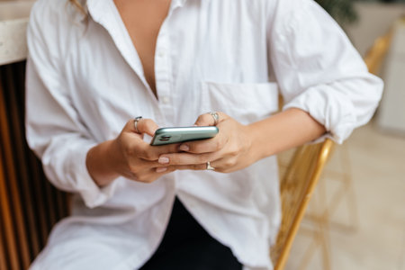 Woman typing text message on smart phone in a cafe.の写真素材