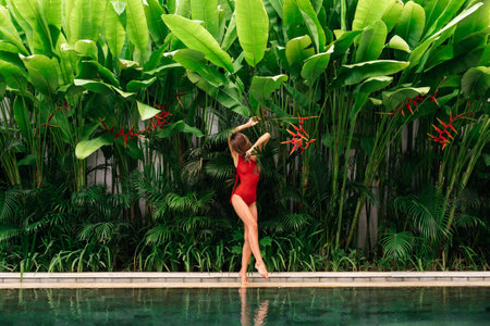 Colorful portrait of pretty young woman in red swimsuit near swimming pool.の写真素材