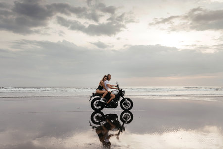 Young couple riding motorcycle on the beachの写真素材