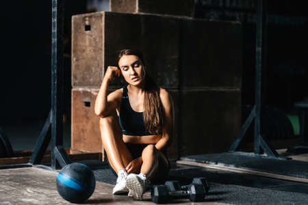 Fit young woman at a crossfit style on dark gray background.