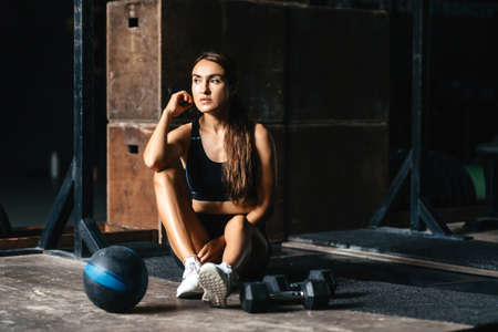 Fit young woman at a crossfit style on dark gray background.の写真素材