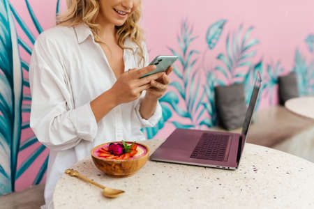 Woman typing text message on smart phone in a cafe.の写真素材