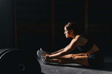 Fit young woman at a crossfit style on dark gray background.の写真素材