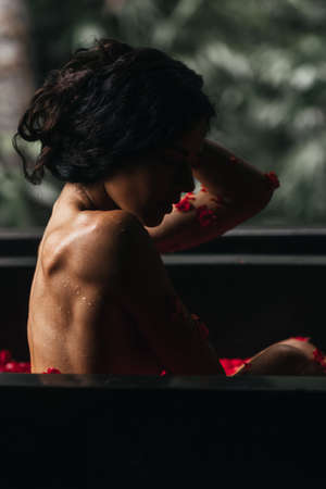 Woman relaxing in round outdoor bath with tropical flowers, organic skin care, luxury spa hotel,の写真素材