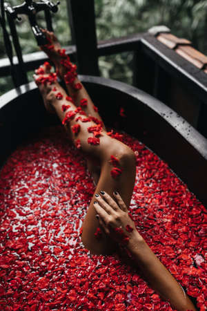 Beautiful female legs in bath with rose petal. Body care.の写真素材