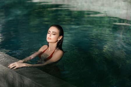 Young pretty fashion woman posing outdoor in summer in bikini on poolの写真素材