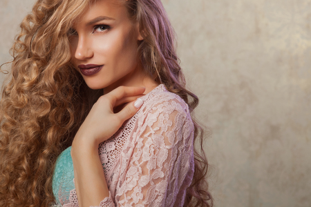 Blonde woman with fashion make-up and curly hair in vintage bedroom. Skin and hair care conceptの写真素材