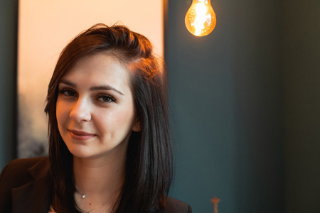Close up portrait of beautiful dark-haired model with a light bulb on background. Copy space. Mock upの写真素材