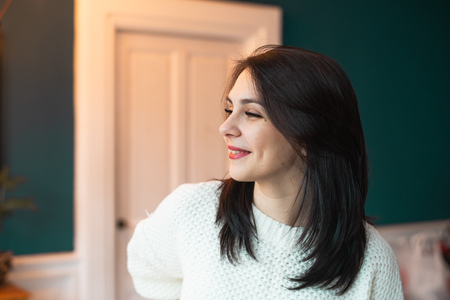 Beautiful woman smiling in white sweater, looking awayの写真素材