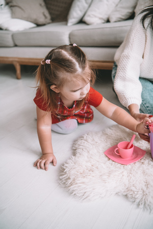 Little girl playing toy baby dishes at homeの写真素材
