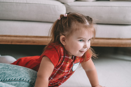 Close up little adorable thoughtful girl dreaming lying on a floor in a living room at modern homeの写真素材