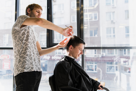 Mens hairstyling and haircutting in a barber shop or hair salonの写真素材