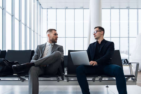 Businessmen working together on laptop in airport loungeの写真素材