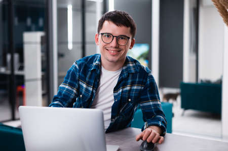 Portrait of handsome young man working remotely at home and smiling happily at camera