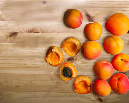 Whole and cut ripe apricots isolated on a wood backgroundの写真素材