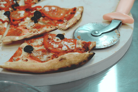 Sliced Pizza on the desk  close-up fashionable toned photoの写真素材