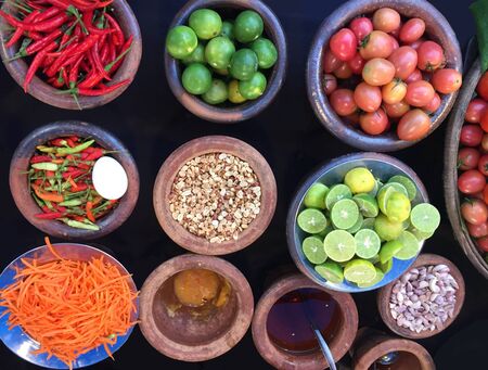 Rustic style raw vegetables, spices in clay or ceramic pots. Top view organic vegetables tomato, hot pepper, carrot, lime in a bowls.の写真素材