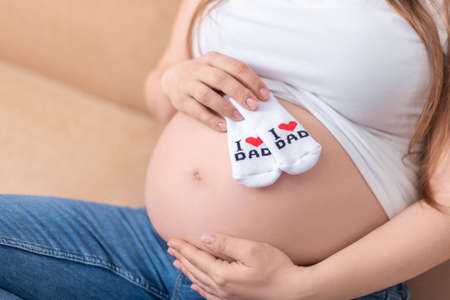 baby socks with the inscription I love dad on a pregnant belly
