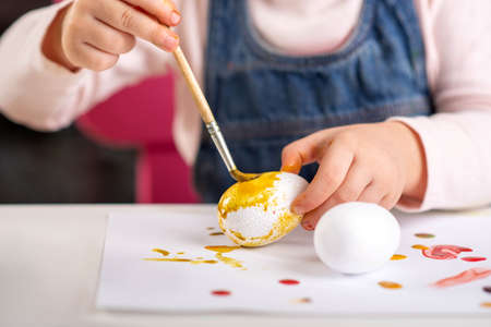 a child paints eggs with paintsの写真素材