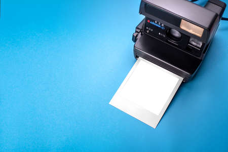 instant camera on a blue background with a white sheet of paperの写真素材
