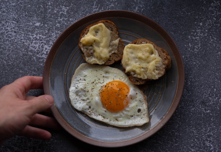 Fried eggs with bread on a plate on a dark background.