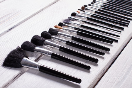 Different natural brushes for professional make-up. Brush on a wooden background.