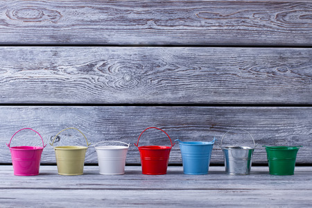 Small decorative buckets on gray wooden background. Place for your text.の写真素材