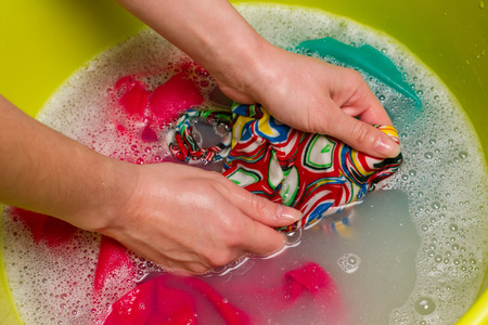 Female hand wash clothes by hand in a bowl.