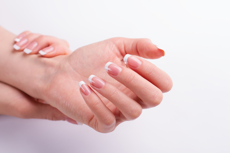 Beautiful well-groomed female hands. Classic French manicure on a white background.の写真素材