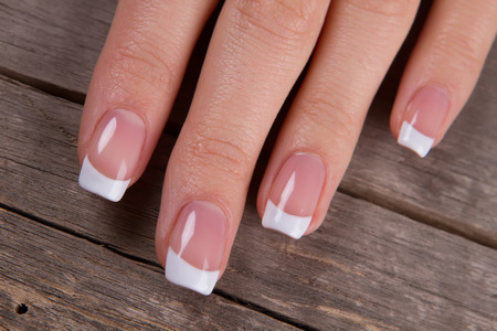 Close-up of female fingers. French manicure on a vintage wooden background.の写真素材