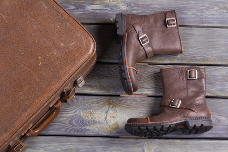 Men's leather boots and old retro suitcase on a wooden background.の写真素材