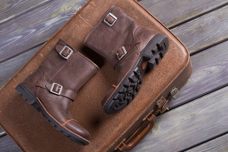Stylish men's boots lie on retro suitcase.