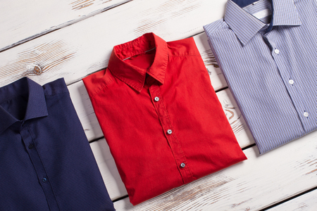 Business modern men's shirts with different colors and prints on white wooden background.の写真素材