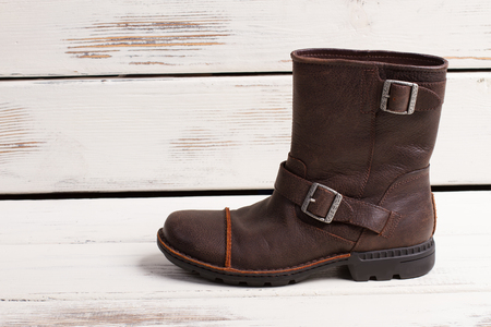 Beautiful stylish pair of men's winter boots with fur. Men's shoes on retro wooden background.の写真素材