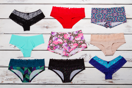 Many multi-colored women's panties. Background of pants. Pants and shorts on a wooden background.の写真素材