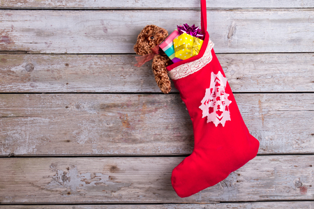 Christmas decoration stocking with toy and gifts hanging on rustic wooden background.の写真素材