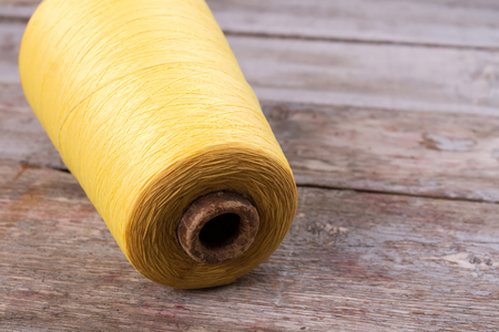 Beautiful big skein of yellow yarn on the vintage background. Thin woolen threads for knitting.