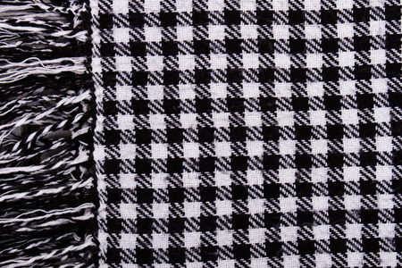 Background with black and white checkered scarf. Checkered knitted scarf with fringe.の写真素材