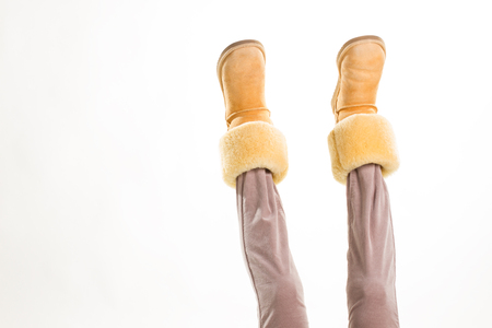 Female feet in winter yellow shoes lifted up.