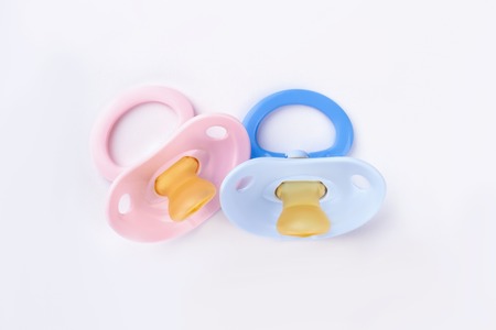 Pink and blue baby silicone pacifiers. White isolated background.