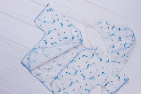 Set of white newborn baby cloth. Shirt and hat. White wood background.の写真素材