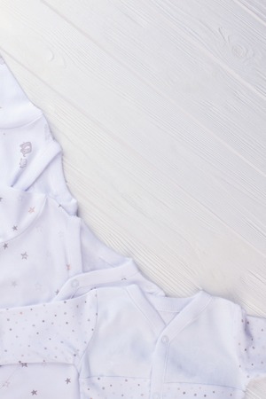 Baby pajamas on wood with copyspace. White wooden desk background.