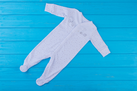 White newborn footed onesies. Blue wood background.の写真素材