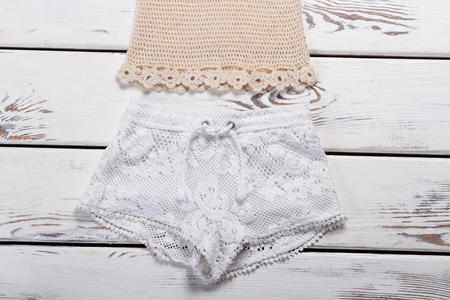 Lady's beige knitted tank top. Knitted handmade garment on white shelf. Woman's tank top on sale. Summer clothing at discount.の写真素材